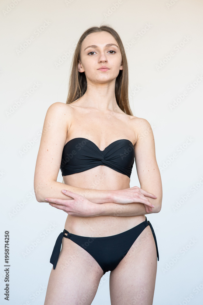 Fototapeta premium Portrait of smiling young woman with natural makeup looking at camera. Clean beauty model agency test shot with soft light, minimal style, fresh skin, neutral background, authentic face expression
