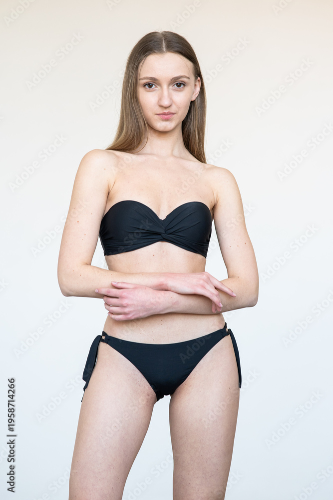 Fototapeta premium Portrait of smiling young woman with natural makeup looking at camera. Clean beauty model agency test shot with soft light, minimal style, fresh skin, neutral background, authentic face expression