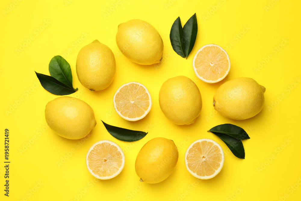 Fototapeta premium Ripe lemons and leaves on yellow background, flat lay