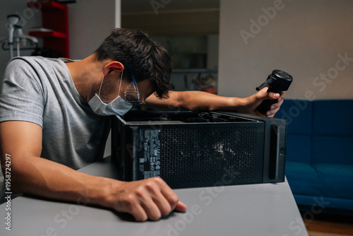 Fotografi Side view of technician in face mask and safety glasses cleaning computer case using small vacuum cleaner, demonstrating proper maintenance procedures