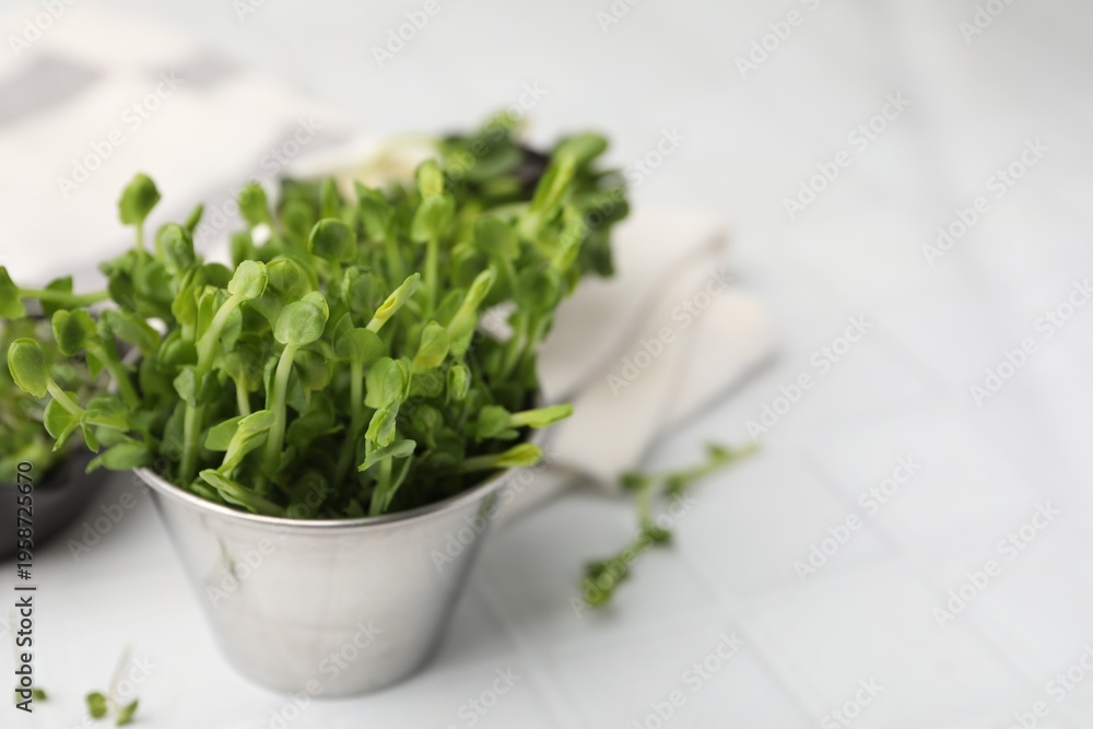 Fototapeta premium Fresh microgreens on white tiled table, closeup. Space for text