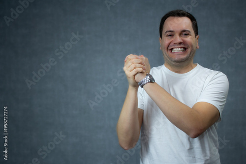 Happy mid-adult man smiling with hands clasped. Horizontal studio portrait with ample lateral copy space, ideal for approval, affirmative gesture, and partnership concept.