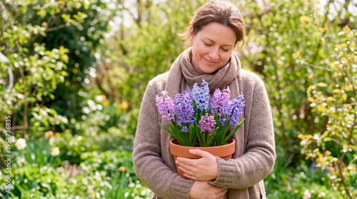 Woman smiling while holding potted hyacinth in spring garden  