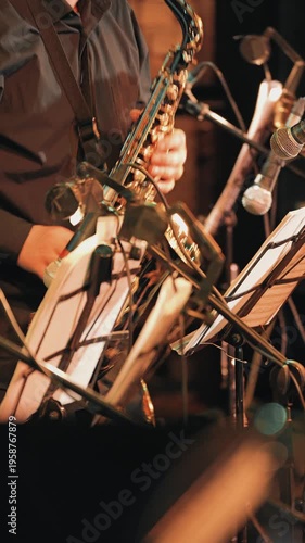 Close up of a musician playing saxophone at a jazz club. Warm, atmospheric stage lighting and a shallow depth of field focusing on the instrument and the hands of the performer