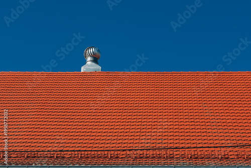 Red Tile Roof With Turbine Ventilator Under Blue Sky