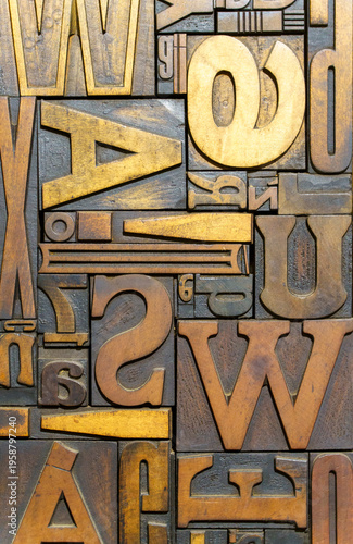 Vintage wooden typesetting letters and blocks for traditional letterpress printing. A close-up background showing old weathered typography stamps with various fonts and characters.