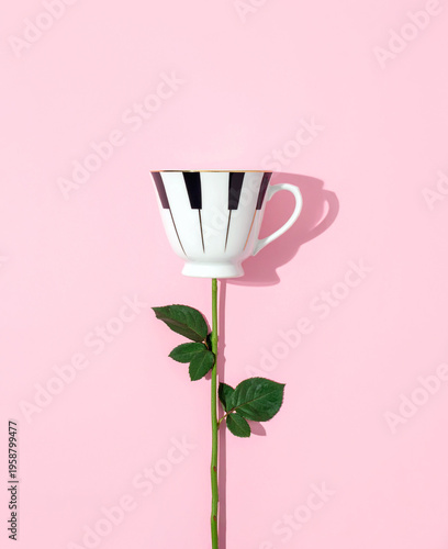 Creative piano keyboard mug on a green rose stem over pink background , conceptual music and nature metaphor