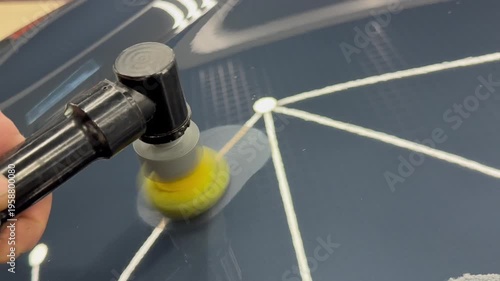 A car service worker polishes the car body with a polishing machine. Detailing and polishing of the car. Car detailing - hands with an orbital polishing machine in an auto repair shop. PDR. 