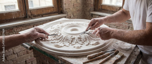 Artisans restoring plaster rosette ornament with carving tools