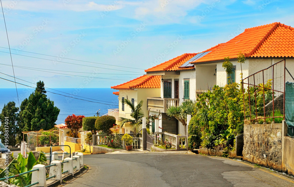 Obraz premium Coastal Houses With Orange Tile Roofs on a Sunny Seaside Street Overlooking the Ocean in Madeira
