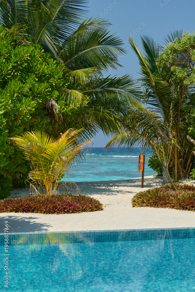 Fototapeta premium Classic Maldives island landscape on a sunny day, coastal luxury resort buildings, azure water, white sand, palm trees on the shore