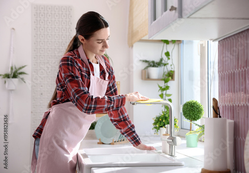 Φωτογραφία Cleaning service worker wiping faucet of kitchen sink with rag indoors