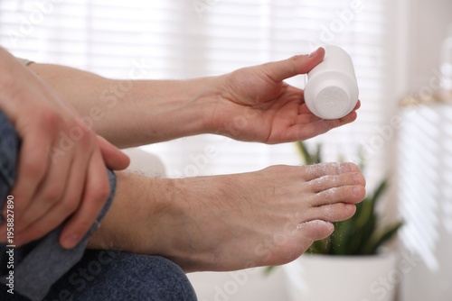 Obraz na płótnie Man applying talcum powder onto his foot at home, closeup