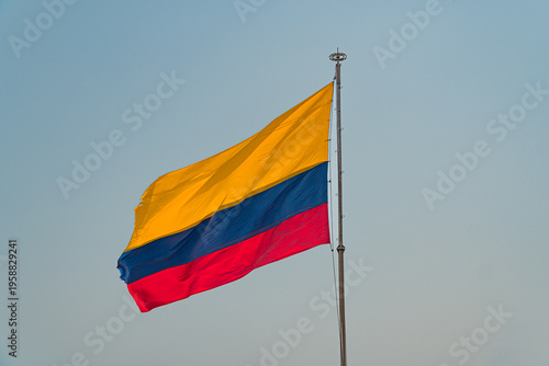 Fotografi Colombian National Flag Waving on Flagpole Against Blue Sky