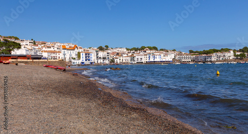 Pebble beach and waterfront houses in Cadaques on sunny day, Catalonia, Spain