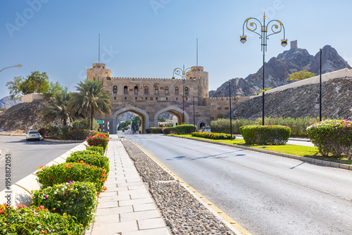 Muscat, Oman – December 28, 2025: Historic Muscat Gate with traditional stone architecture and arched entrance at the old city, surrounded by mountains under clear blue sky.