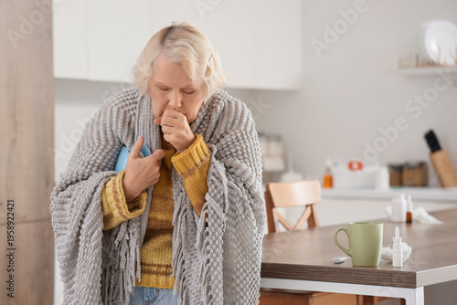 Photography Sick elderly woman with hot water bottle coughing in kitchen