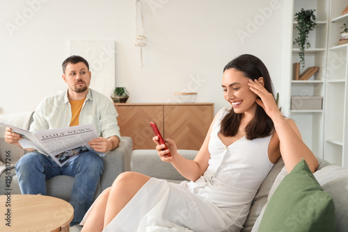 Young woman texting lover and her husband at home. Cheating concept
