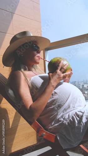Expectant mother enjoying a refreshing coconut water drink while resting on a deck chair