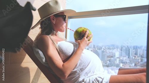 Expectant mother enjoying a refreshing coconut drink while relaxing in a hammock on a sunny day