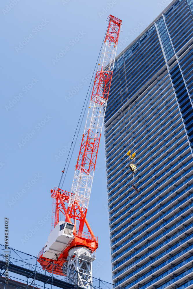 Fototapeta premium 建設中の高層ビルと赤白のタワークレーン