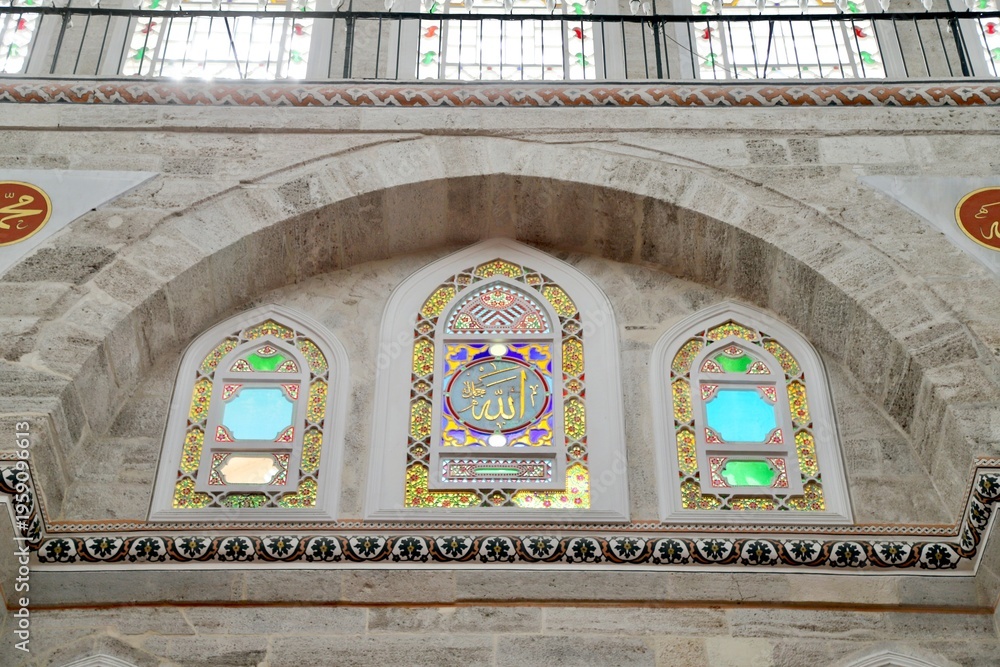 Obraz premium The stained-glass windows of the historic Mihrimah Sultan Mosque in Istanbul, featuring the name of Allah in the central panel
