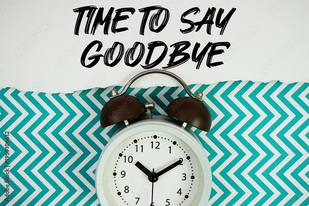 Fototapeta premium Time To Say Goodbye text written on paper rip with alarm clock flat lay on turquoise chevron background
