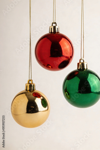 Three Shiny Gold Red and Green Christmas Bauble Ornaments Hanging on Light Background Illustration