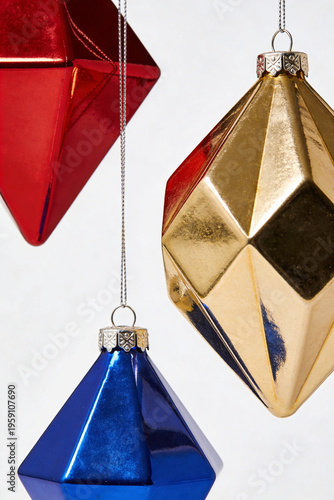 Red Gold and Blue Diamond Shaped Geometric Christmas Ornaments Hanging on White Background Illustration