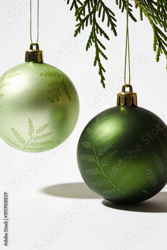 Two Green Christmas Baubles Hanging Under Pine Branch