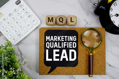 MQL Marketing Qualified Lead text with calculator, magnifying glass and alarm clock on marble background