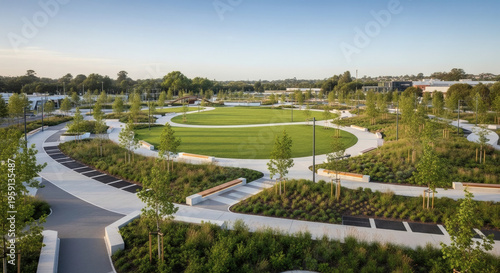 Modern urban park with a prominent circular green lawn, surrounded by winding paved pathways and contemporary landscaped garden beds, designed for relaxation and community.