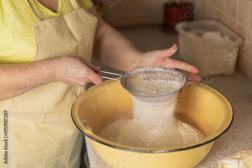 Φωτογραφία Adult woman hands sifting flour over bowl with sieve in kitchen