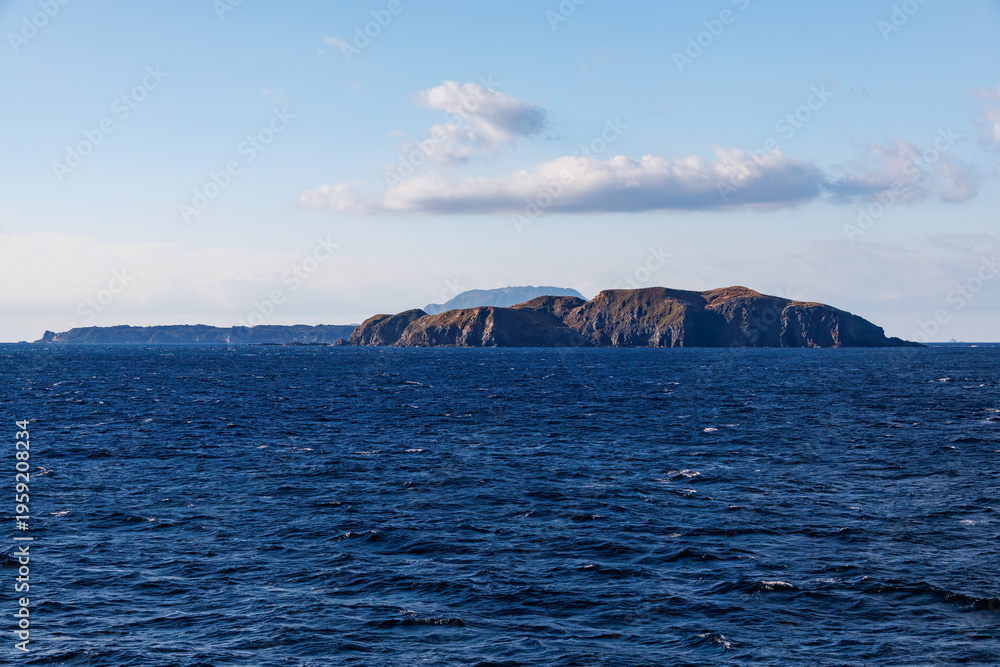 Fototapeta premium 式根島の野伏港、沖に神津島が見える。 新島港に接岸したところ。 東海汽船東京湾～伊豆諸島,太平洋航路のさるびあ船上- 2025 東京の竹芝桟橋を出港して、伊豆諸島の島々を巡るフェリー船、さるびあ丸に乗った。 伊豆大島から新島、式根島を経由して神津島まで到達する。 