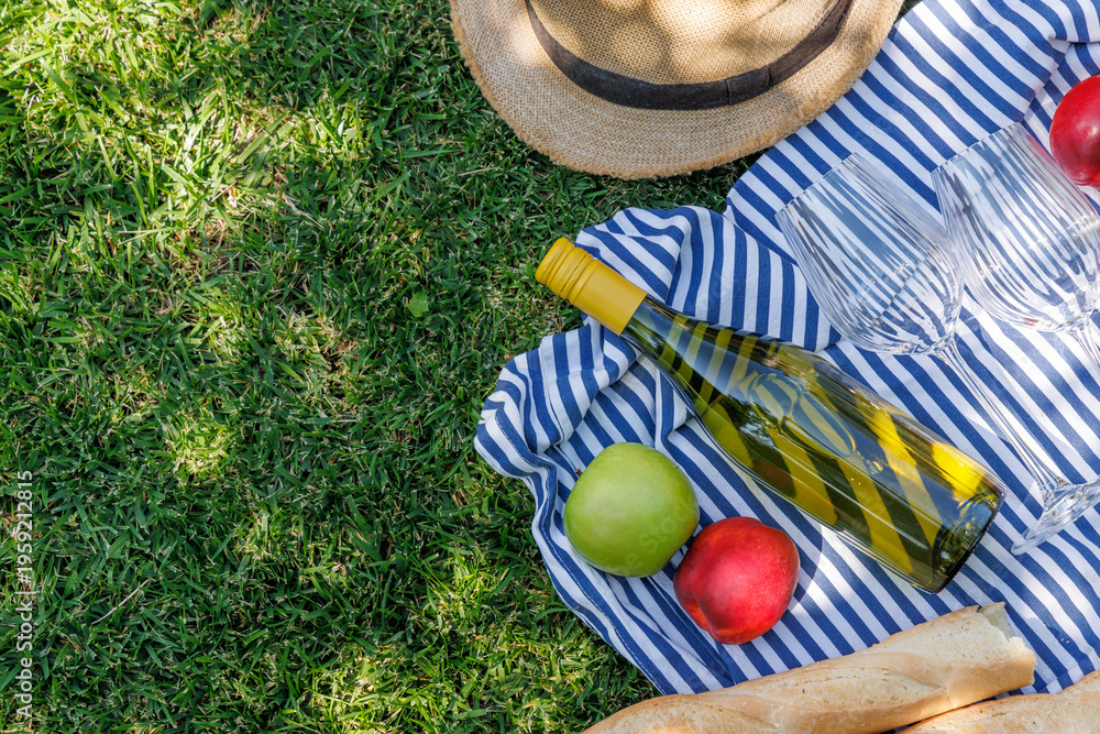 Fototapeta premium Picnic with wine, fruits, and baguette on a green meadow