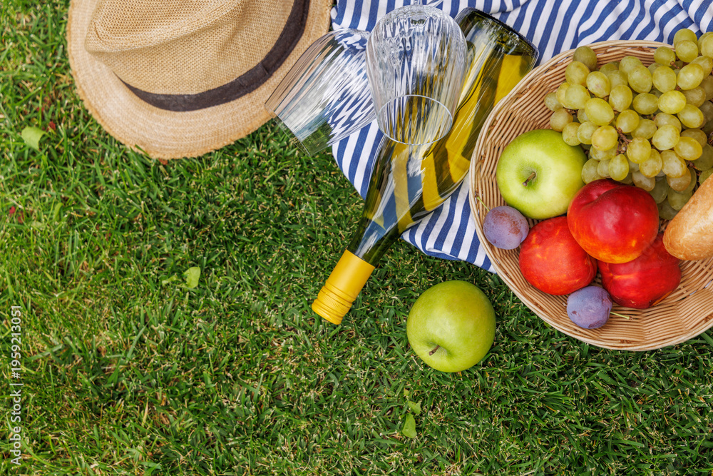 Fototapeta premium Picnic with wine, fruits, and baguette on a green meadow