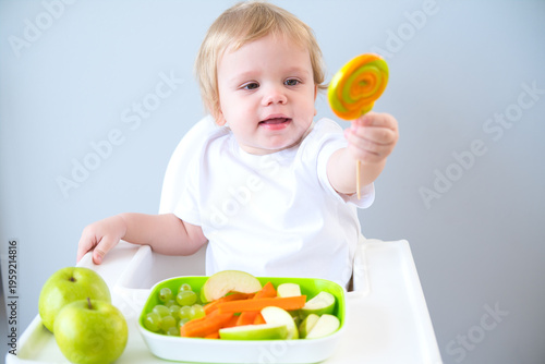 cute baby eating lollipop sitting in a baby chair. weaning