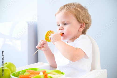 cute baby eating lollipop sitting in a baby chair. weaning