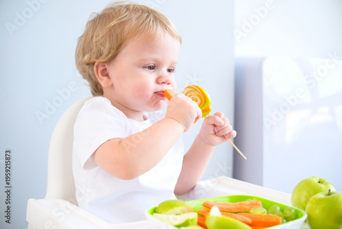 cute baby eating lollipop sitting in a baby chair. weaning