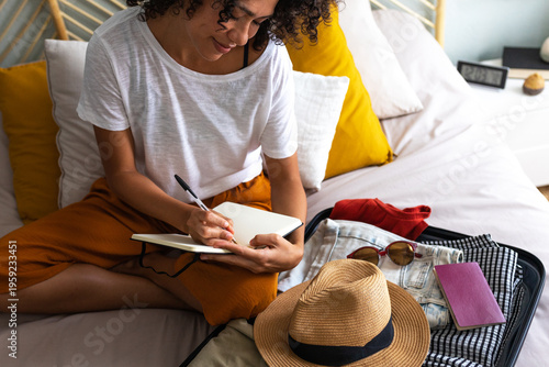 Woman planning trip, writing packing list for vacation