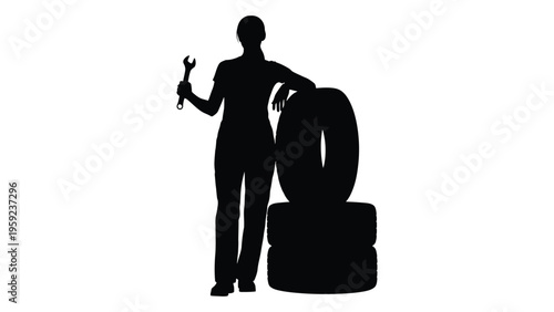 Silhouette of a person standing next to stacked tires holding a tool