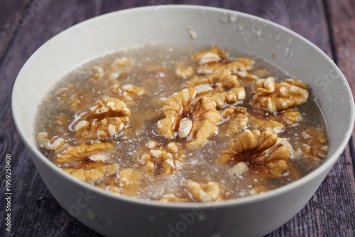Photos Walnuts soaking in water on a wooden table