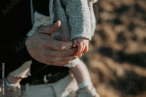 Photos Gros plan d'une main d'adulte tenant délicatement la main d'un petit enfant