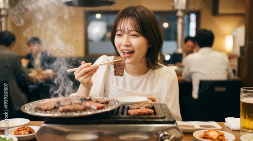 Young Japanese woman about to eat a piece of grilled meat with chopsticks