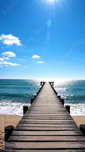 A long wooden pier extends into the ocean on a sunny day at the beach