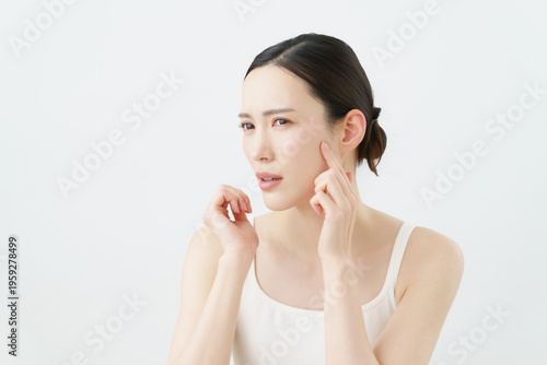 白背景の肌荒れを気にする若い女性