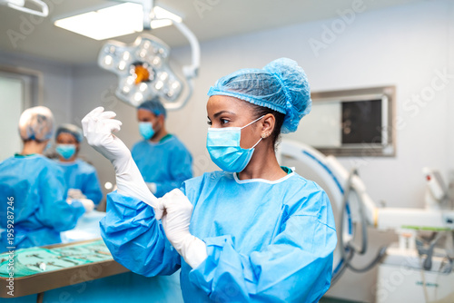 Photos Female surgeon putting on sterile gloves in modern operating room