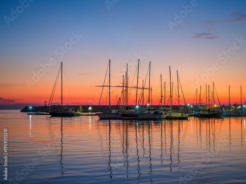 фотографія Sailboats moored in Sciacca marina reflecting vibrant sunset colors