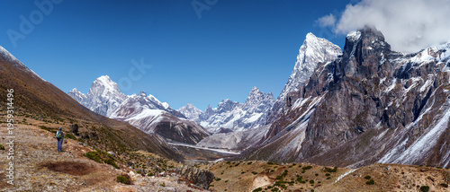 Woman hiker backpacker admiring panoraic landscape on trail during on her trek to Everest Base Camp in Nepal. Beautiful inspirational panoraic landscape, trekking and activity.