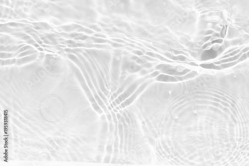 White water with ripples on the surface. Defocus blurred transparent white colored clear calm water surface texture with splashes and bubbles. Water waves with shining pattern texture background.